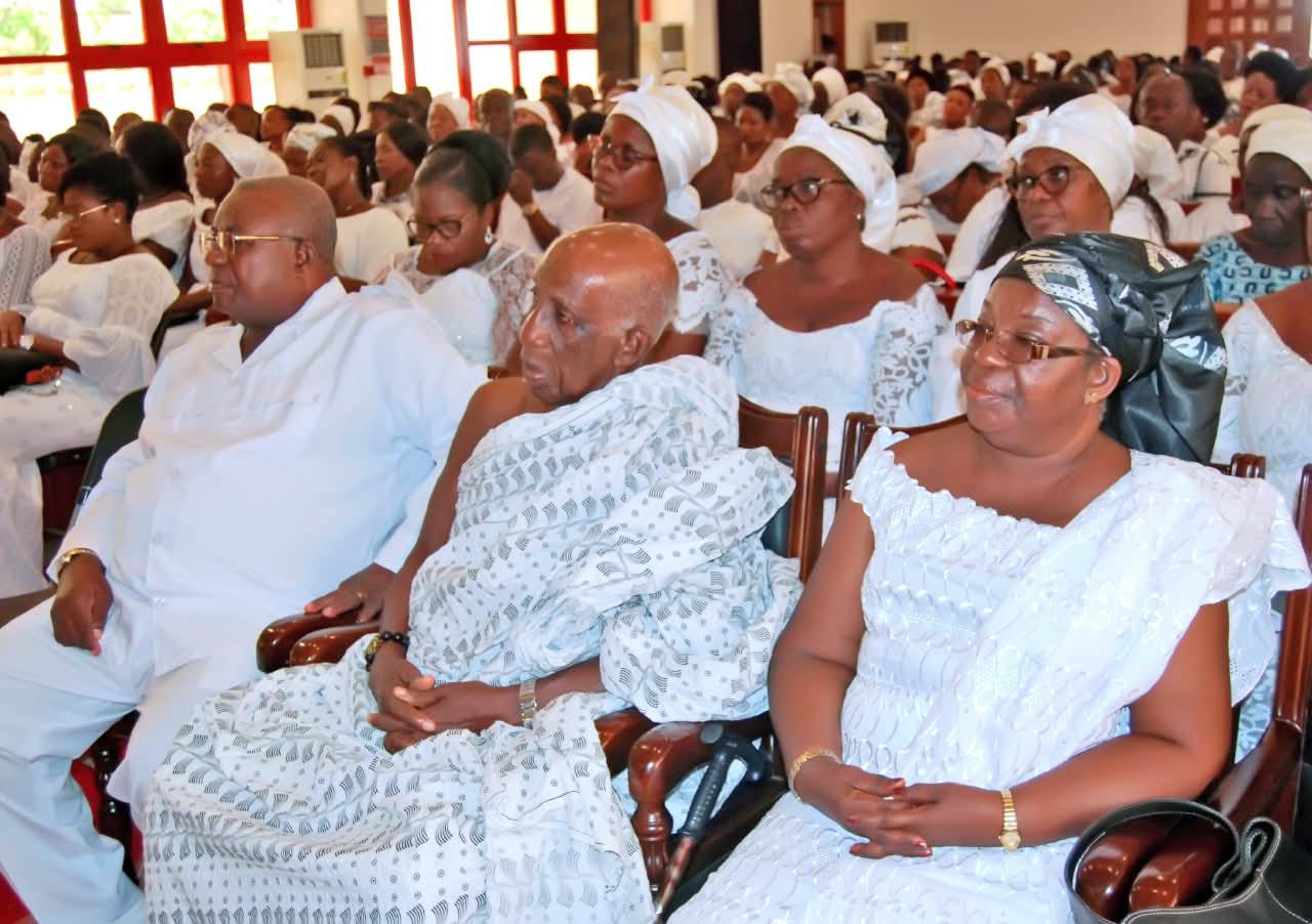 Family heads and elders of the widow seated in the front rows, dressed in ceremonial white woven cloths in solemn remembrance.